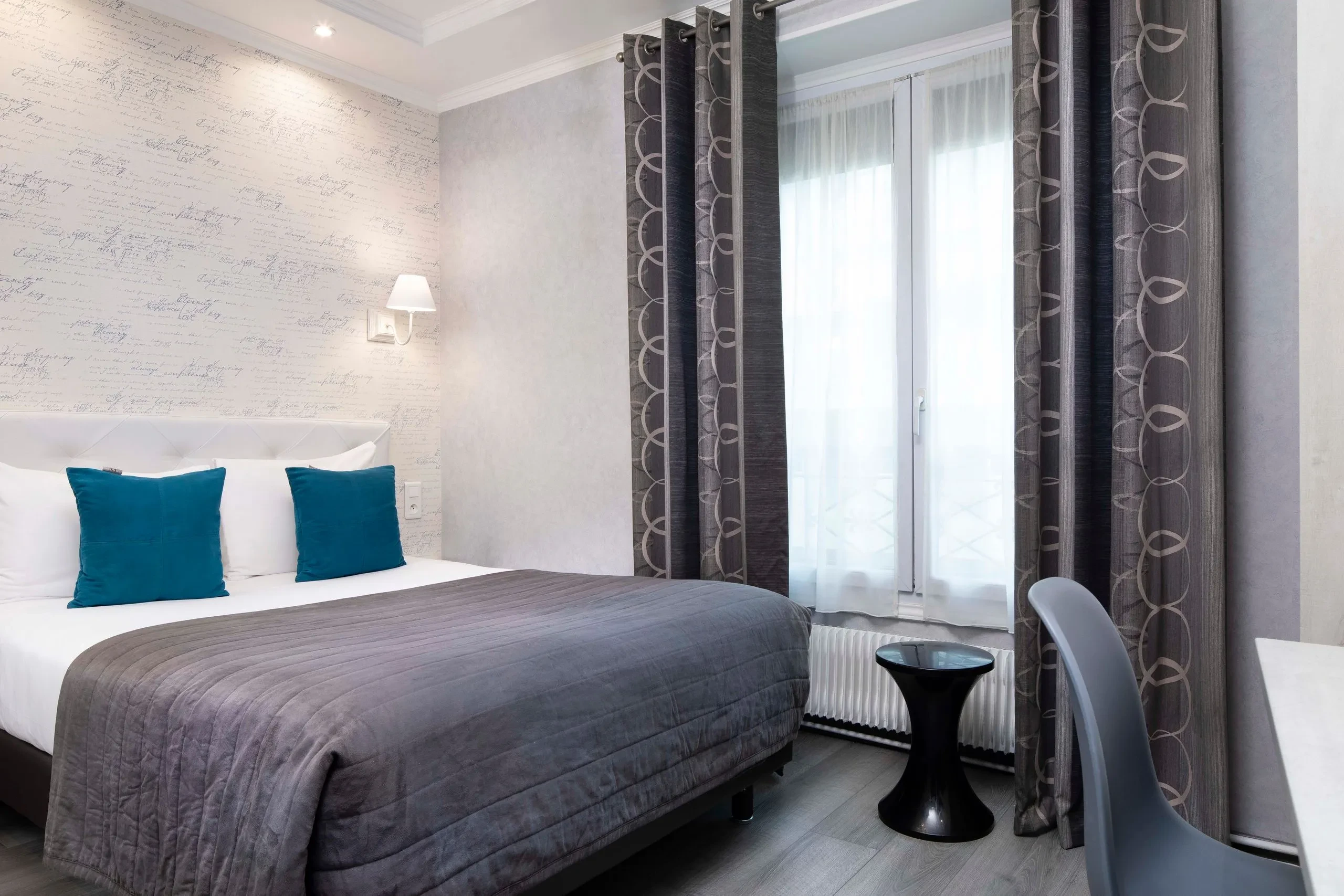 Chambre moderne avec lit double et rideaux gris.