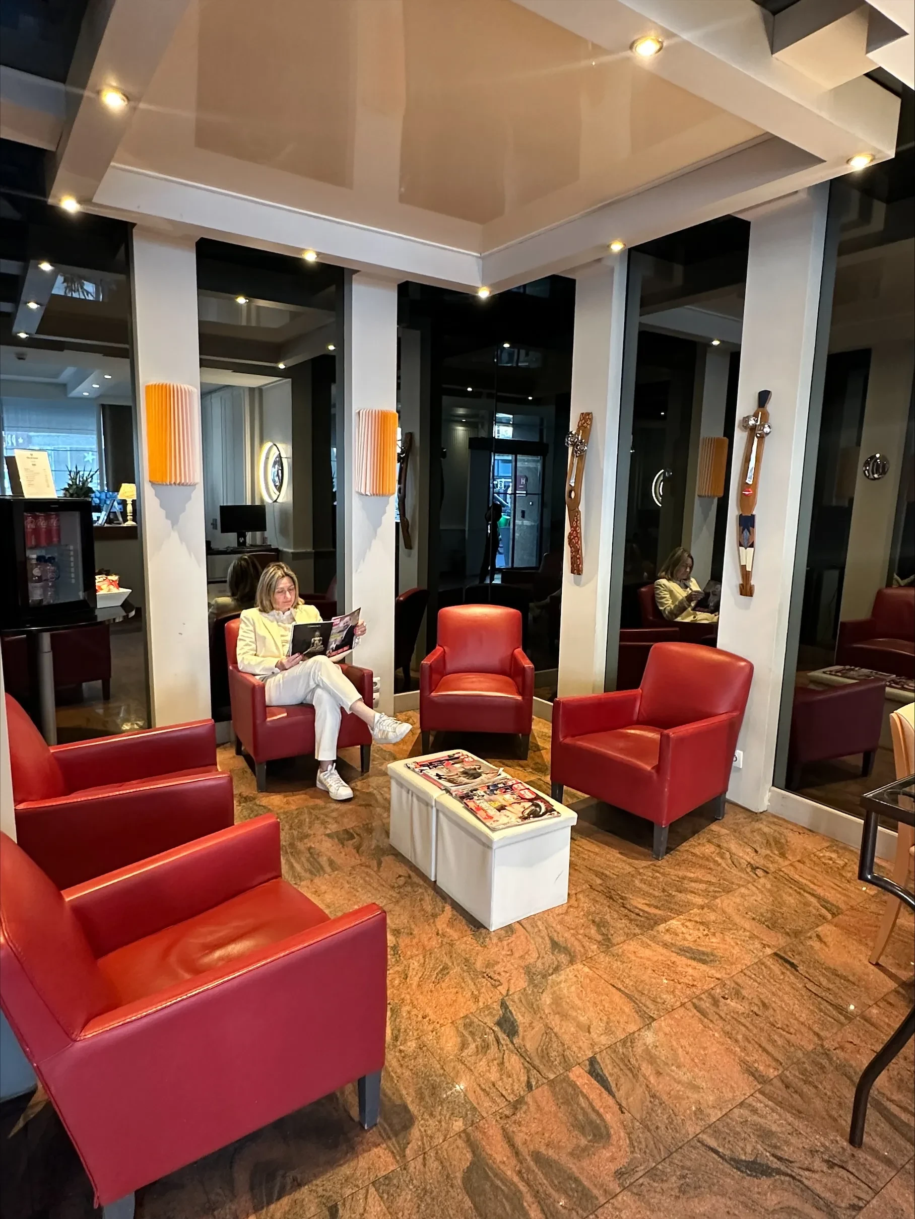 Salle d'attente avec fauteuils rouges et magazines.